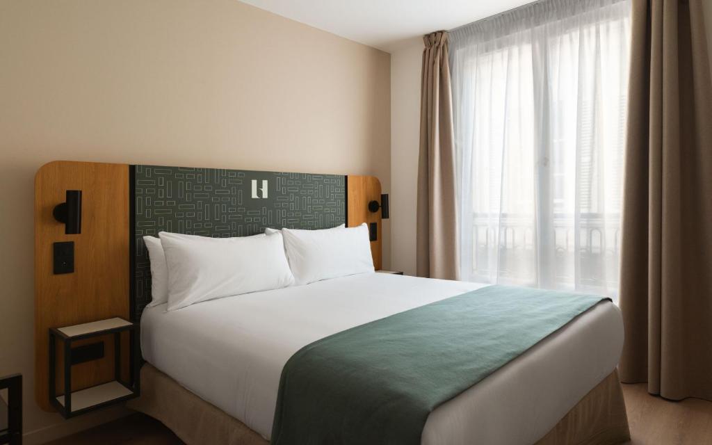 a bedroom with a large bed with a large window at Limehome Versailles Rue du Bailliage in Versailles