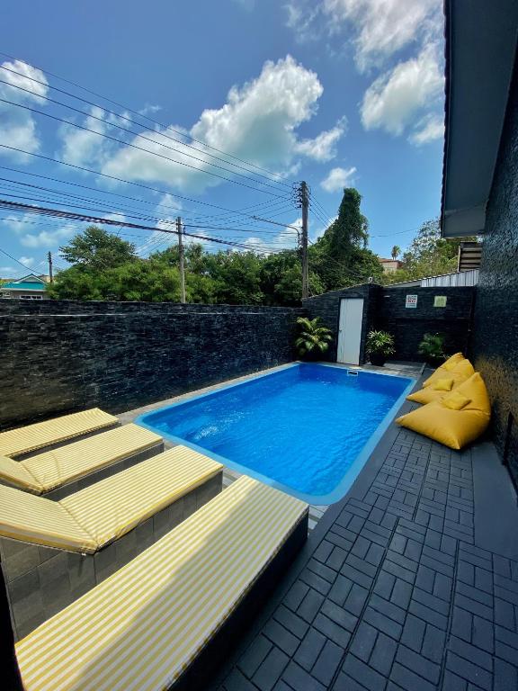 a swimming pool with two chaise lounges next to a wall at L.C. Apartments in Lamai