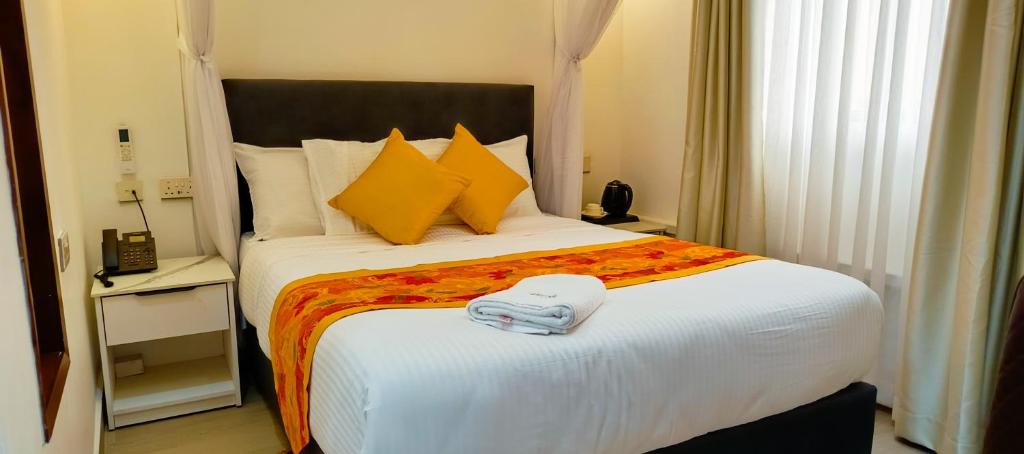 a bedroom with a large white bed with yellow pillows at Bonds Hotel in Nairobi
