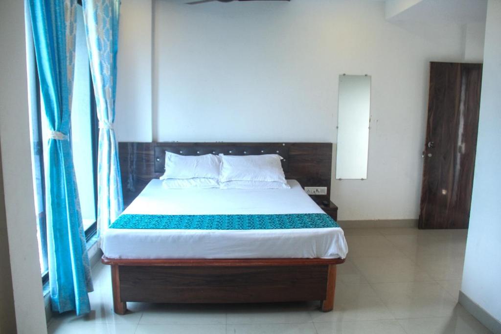 a bedroom with a large bed with blue curtains at SIYA International Lodging And Boarding in Bhiwandi