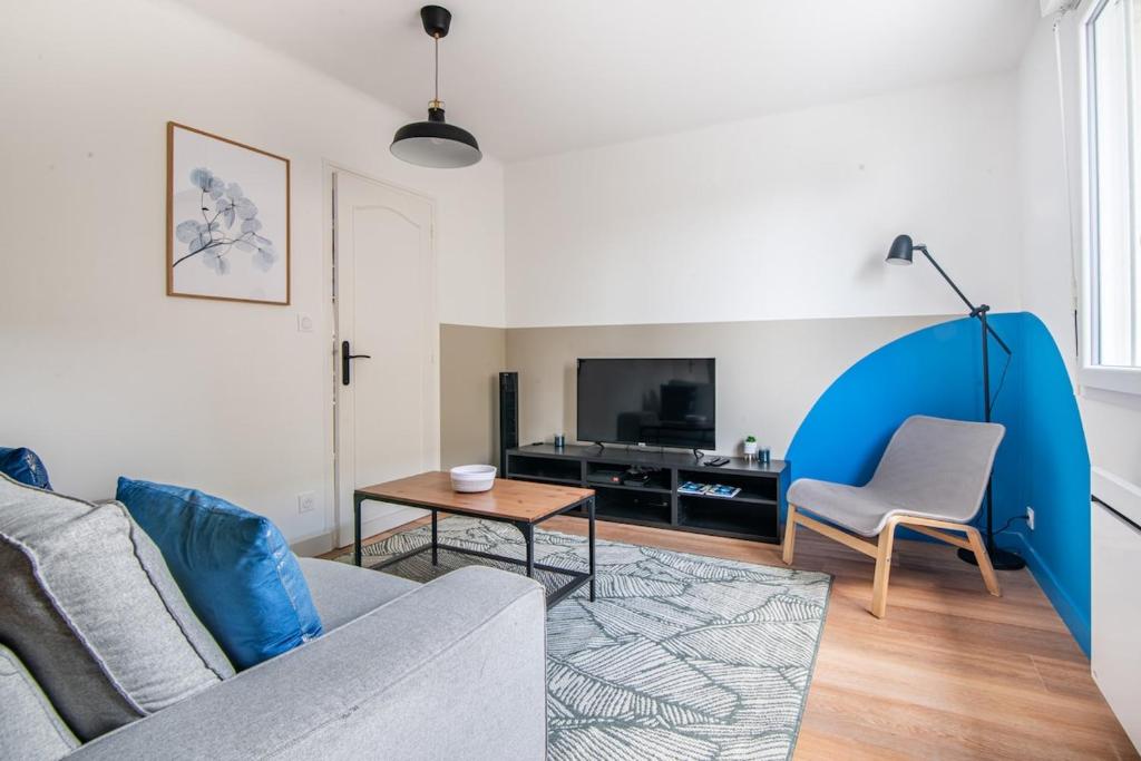 a living room with a couch and a table and a tv at L'Echappée Choletaise, simple et familiale! in Cholet