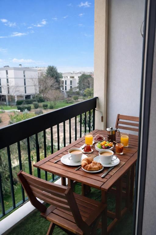 a wooden table with breakfast food on a balcony at Blue lagon-350m plage-clim-parking in Saint-Cyprien-Plage