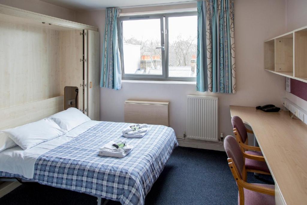 a hotel room with a bed and a desk and a window at International Hall / University of London in London