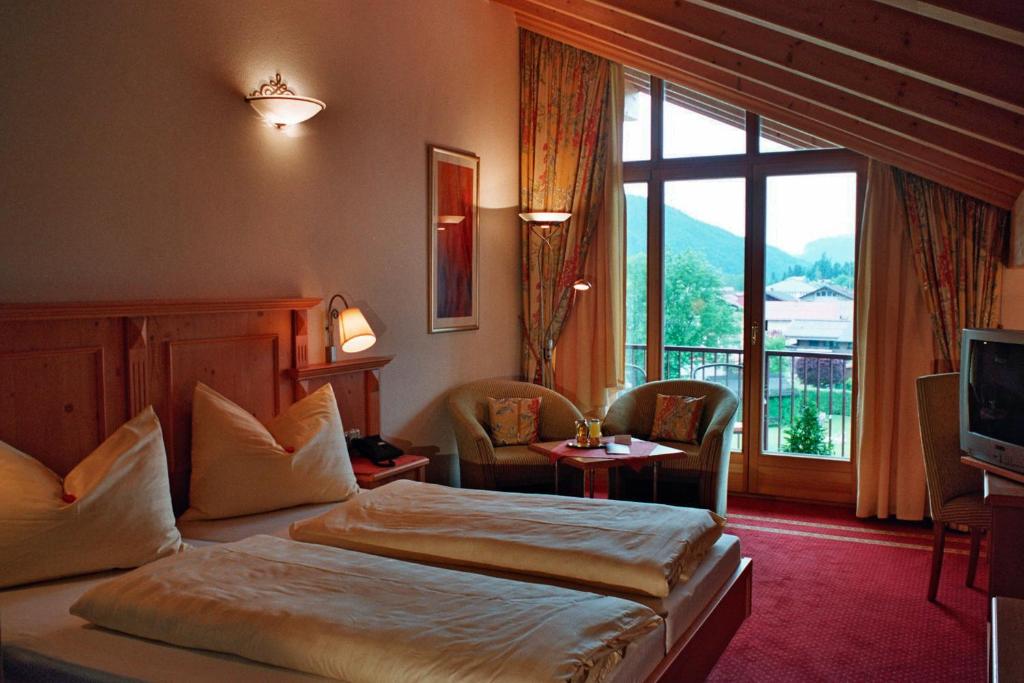 a hotel room with two beds and a large window at Hotel Goldener Stern in Abtenau