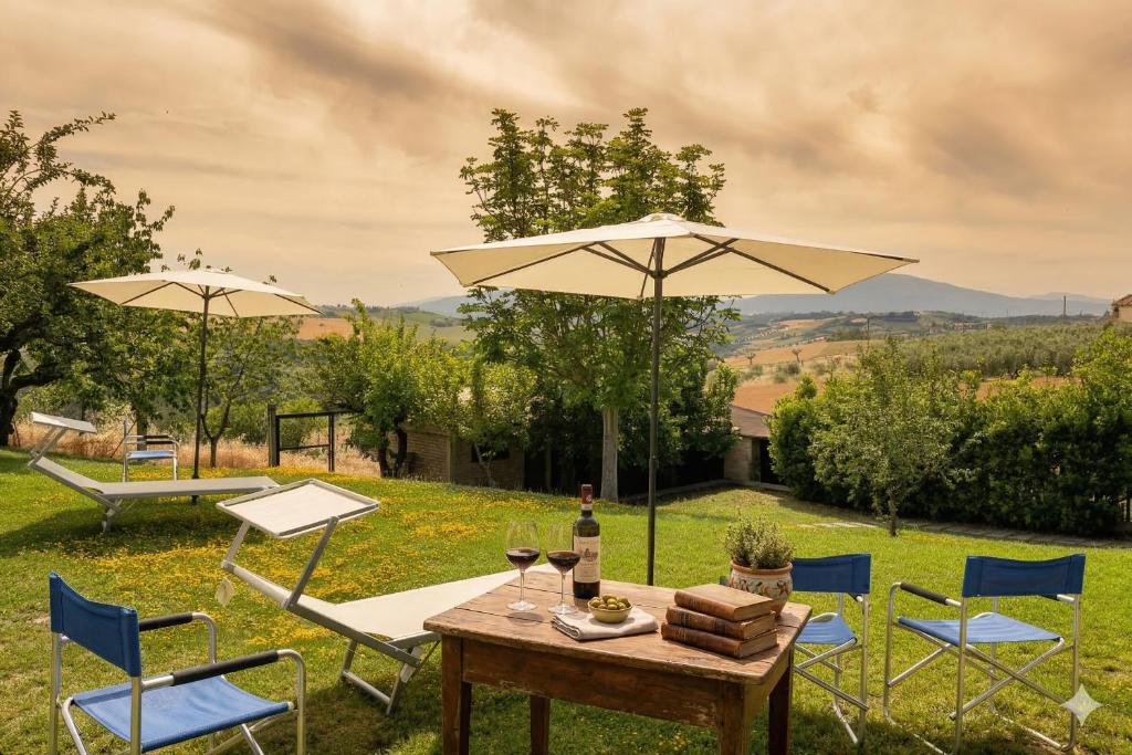 a table and chairs with an umbrella and wine glasses at VILLA TERRABIANCA - Premium Villas in Tortoreto Lido