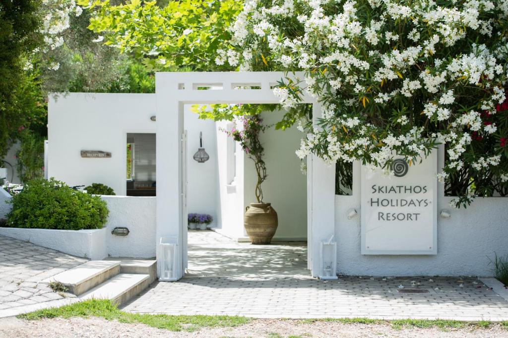 une porte blanche avec un panneau indiquant le complexe de santos haciendas dans l'établissement Skiathos Holidays Suites & Villas, à Vromolimnos
