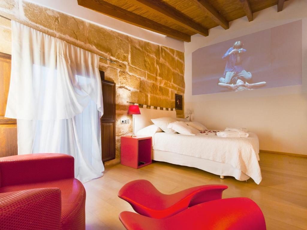 a bedroom with a bed and a red chair at Cas Ferrer Nou Hotelet in Alcudia