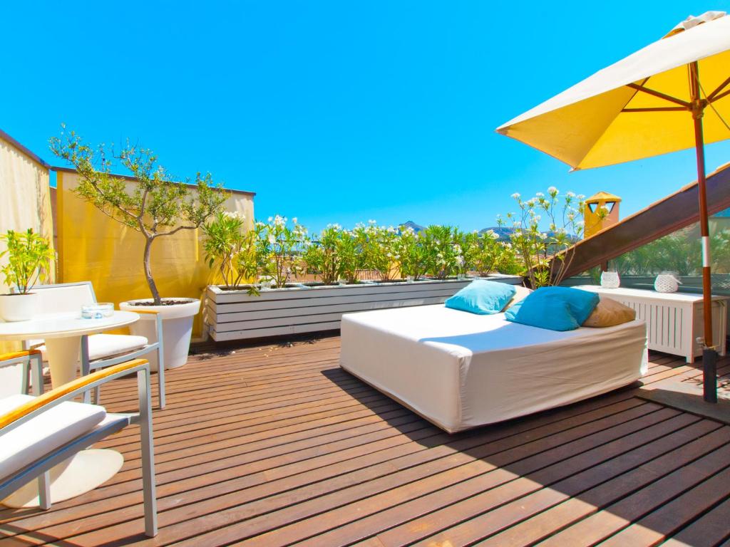 a patio with a bed and an umbrella on a deck at Cas Ferrer Nou Hotelet in Alcudia