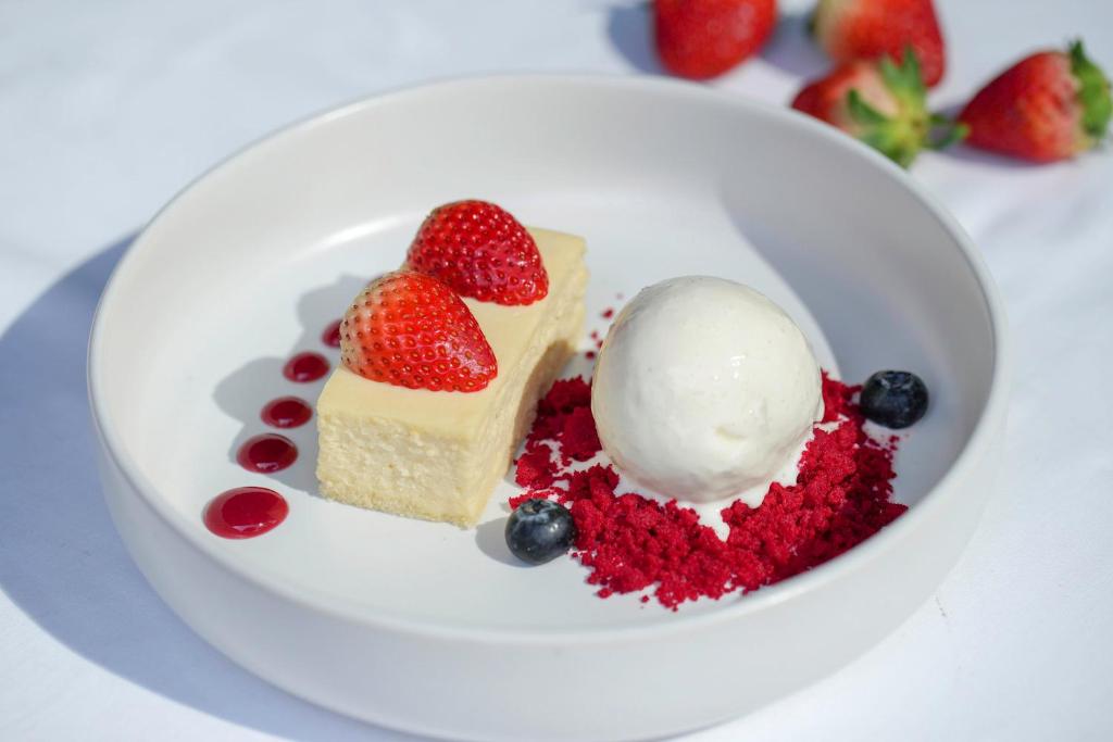 A plated dessert with cake, ice cream, strawberries and blueberries.