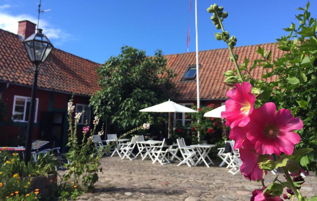 uma flor em frente a um edifício com mesas e guarda-chuvas em Pension Holmegaard em Sandvig