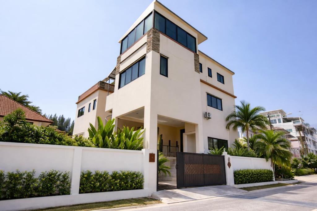 a white house with a fence and palm trees at Rawai 3BR Villa Shared Pool near Shops & Dining in Ban Saiyuan (1)