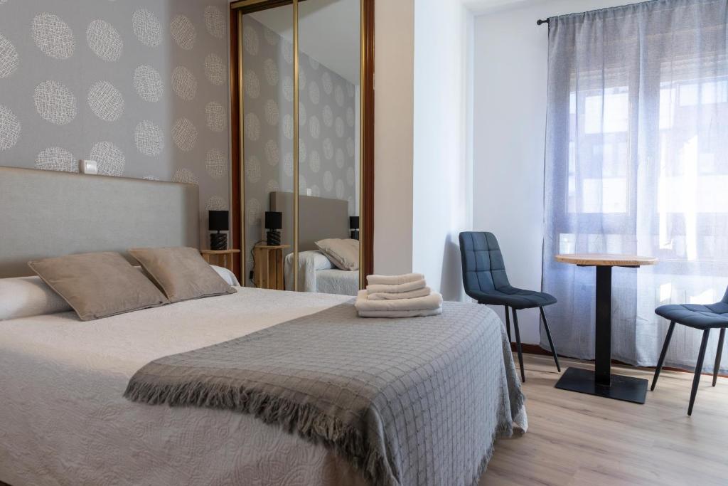 a bedroom with a bed with two chairs and a mirror at Amarantos in Suances
