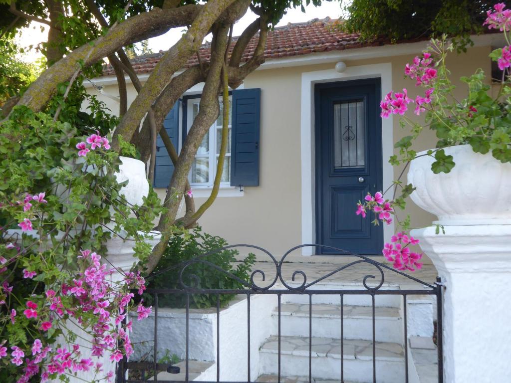 a house with a blue door and pink flowers at Eleni's Cottage in Fiskardo