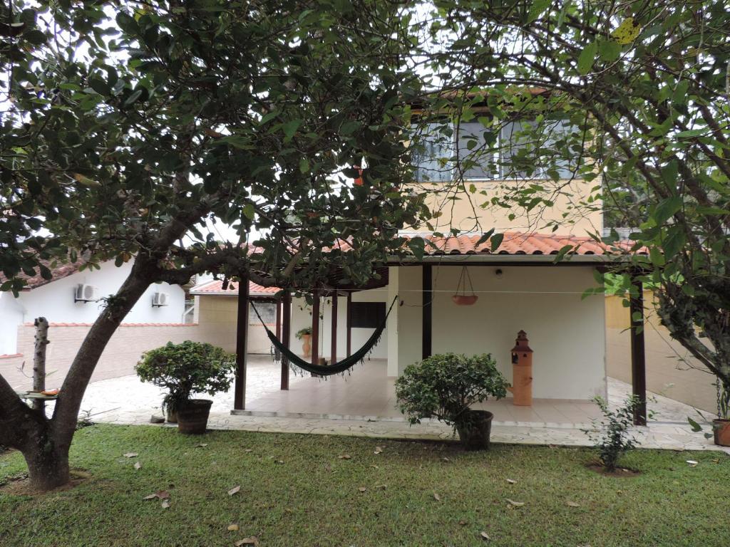 a house with a hammock on the side of it at Casa Orquídeas Ubatuba Praia da Lagoinha in Ubatuba