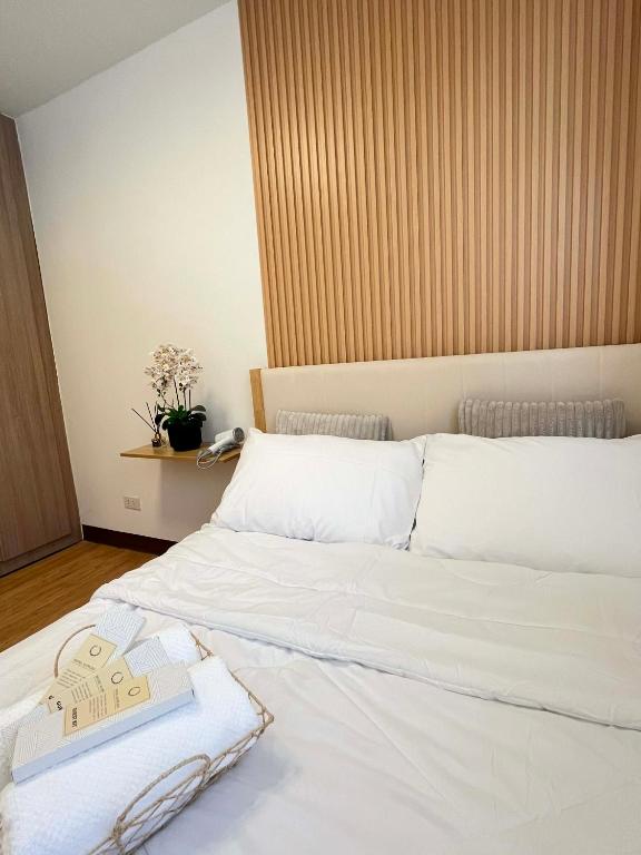 ein Schlafzimmer mit einem weißen Bett mit einem Buch darauf in der Unterkunft Js Place at Arezzo Place Davao in Davao City