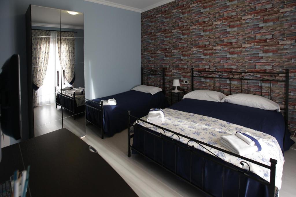 een slaapkamer met 2 bedden en een bakstenen muur bij Number60 in Fiumicino