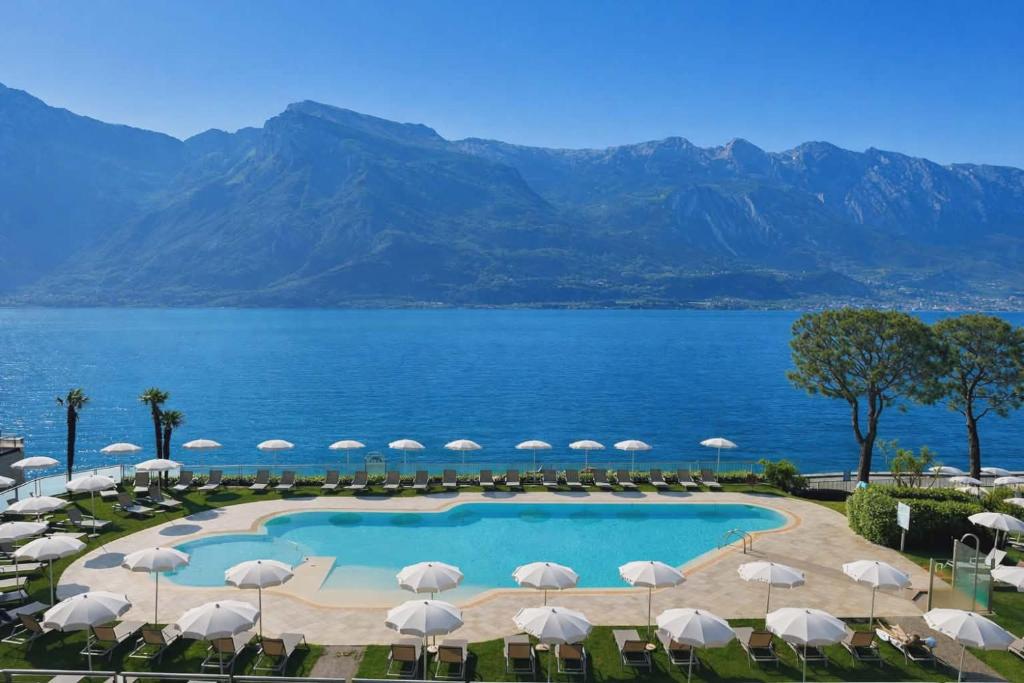 a view of a pool with umbrellas and the ocean at Hotel Du Lac in Limone sul Garda