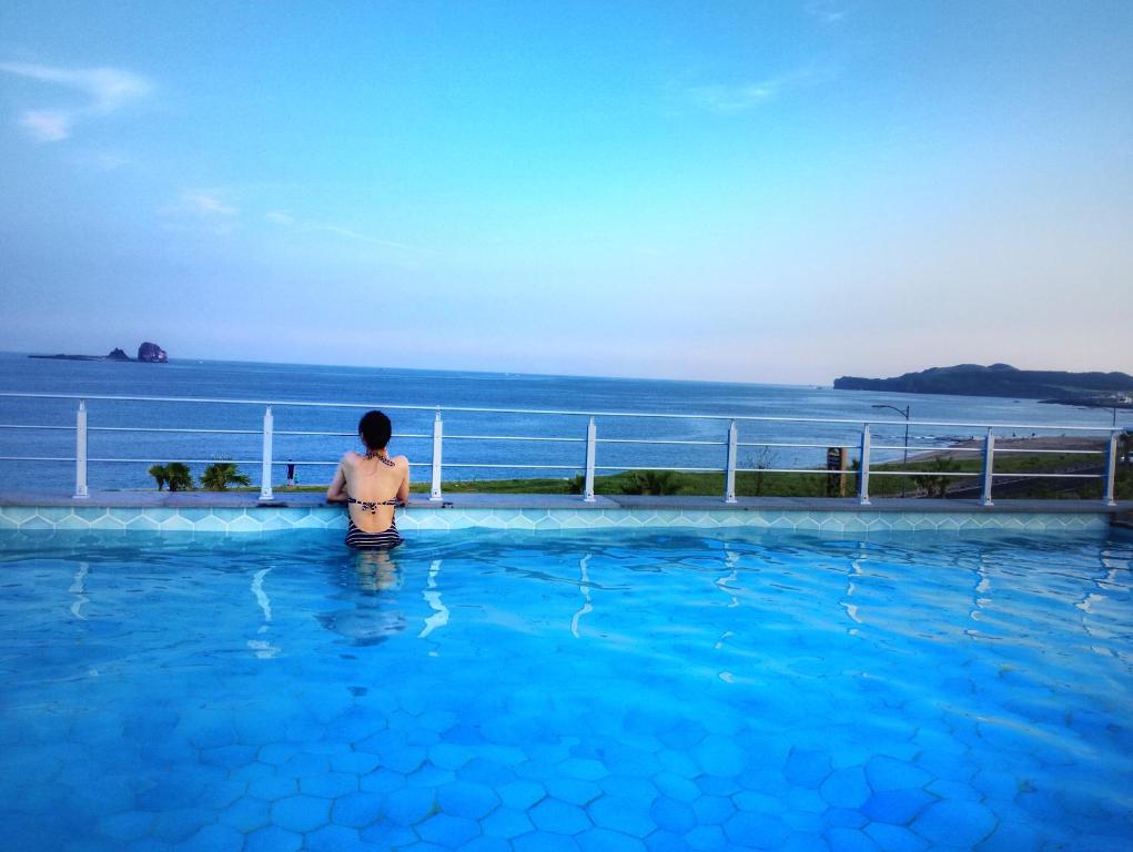 une femme debout dans une piscine donnant sur l'océan dans l'établissement Sun and Moon Resort, à Seogwipo