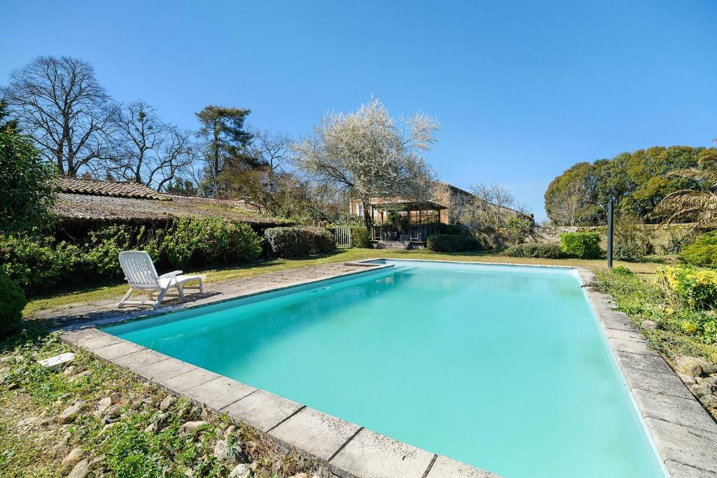 a swimming pool with a chair next to a house at Gite De Marlas in Rieucros