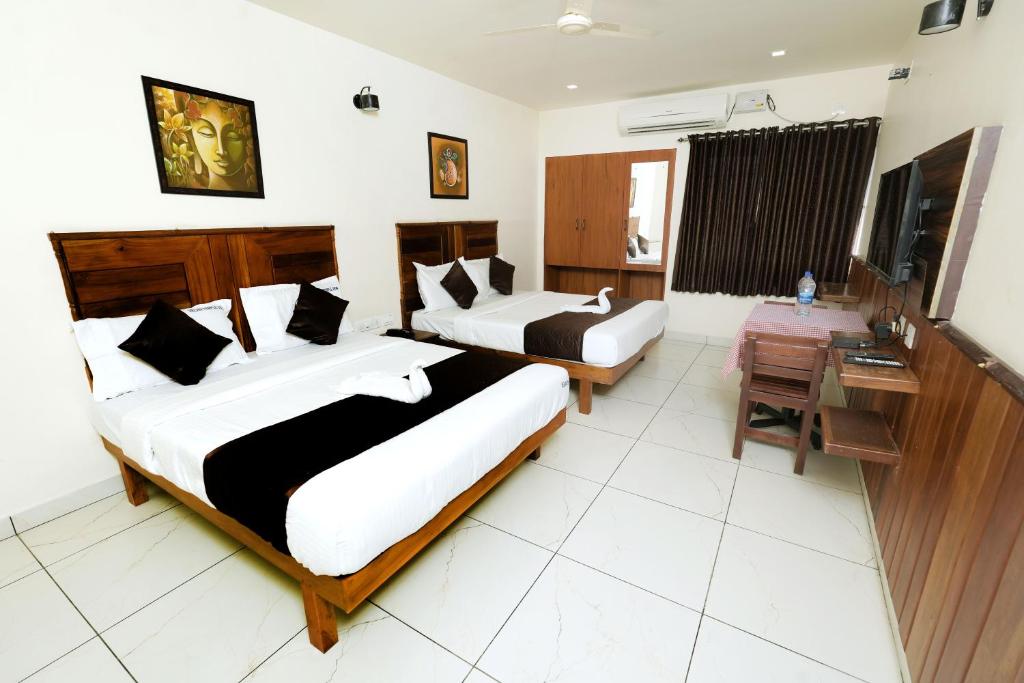 a hotel room with two beds and a desk at Velan Temple View in Palni