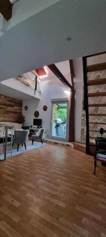 a large room with a wooden floor and a large window at Maison Oscar et Petrus in Beaumont-du-Gâtinais