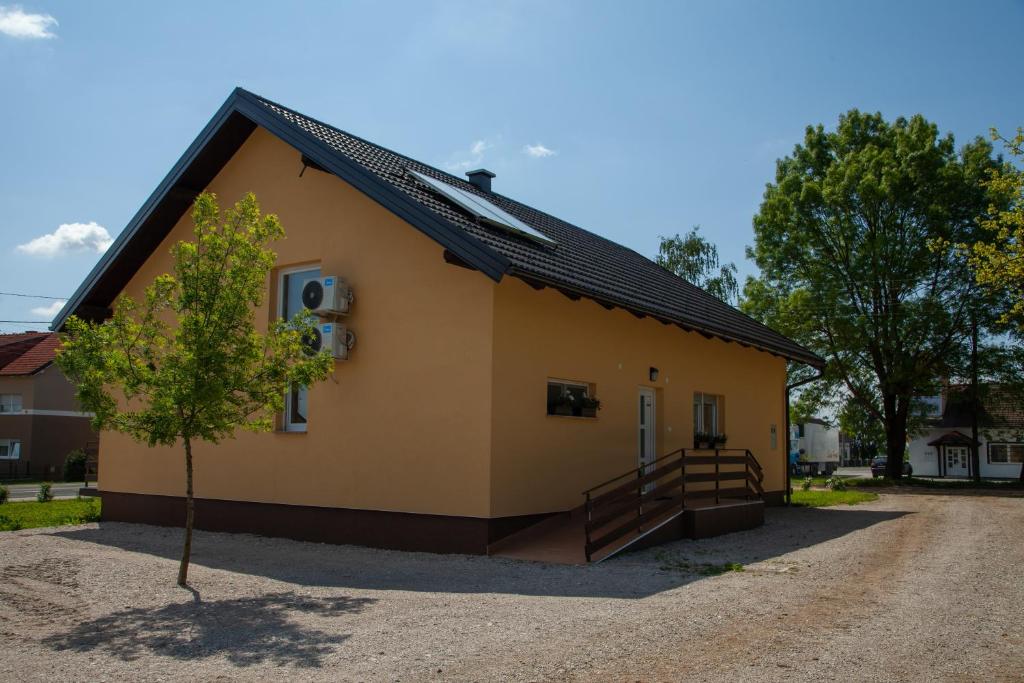 a small yellow house with a tree in front of it at Apartments Slavek in Jastrebarsko