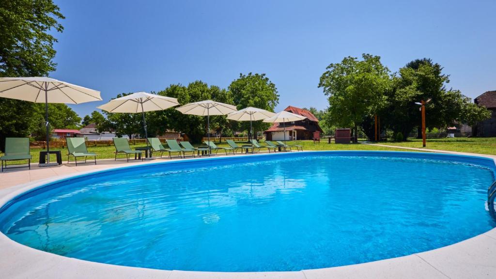 a large swimming pool with chairs and umbrellas at Villa 77 by Villas Guide in Sisak