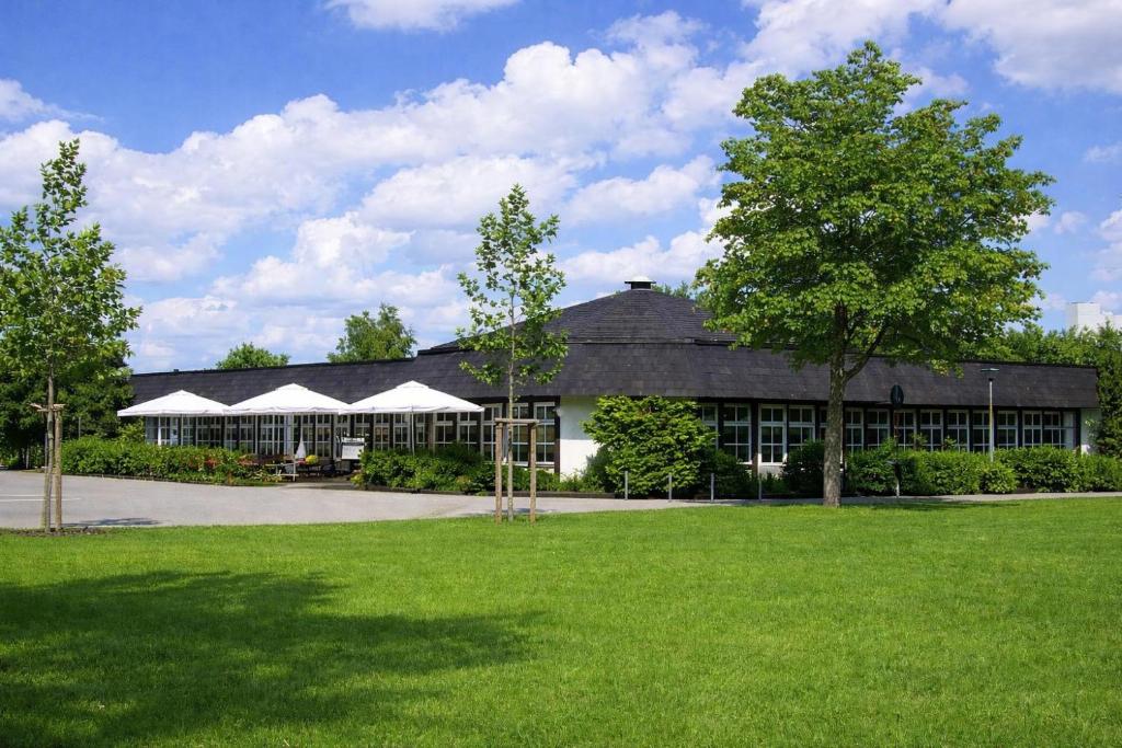 a large building with a green lawn in front of it at Boutique Hotel Wolfsburg in Wolfsburg