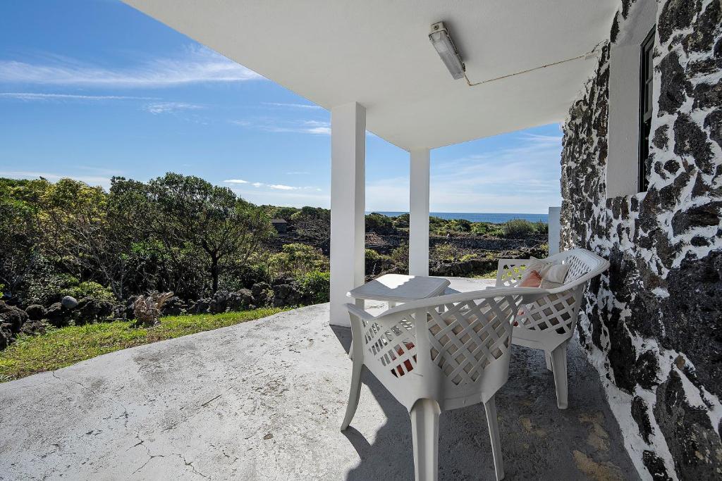 a white table and chair on a patio with a view at Casa Ponta do Biscoito in Lajes do Pico