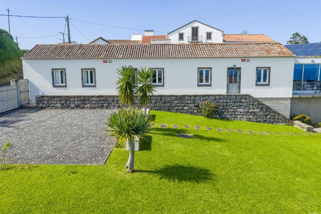 a white house with a yard with palm trees at Casas do Forneiro - T2 in Nordeste