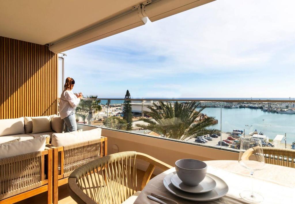 a woman standing on a balcony looking out at the ocean at Apartamento Pink Frontline Premium in Torrevieja