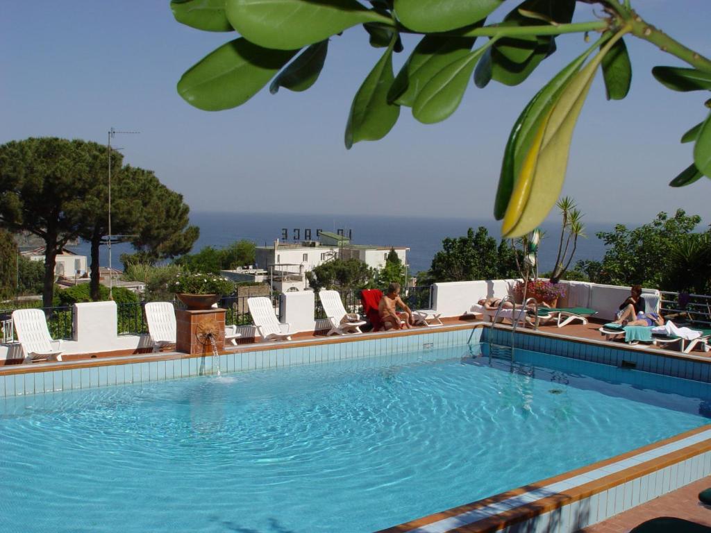 a large swimming pool with lounge chairs and the ocean at Hotel Monti in Casamicciola Terme