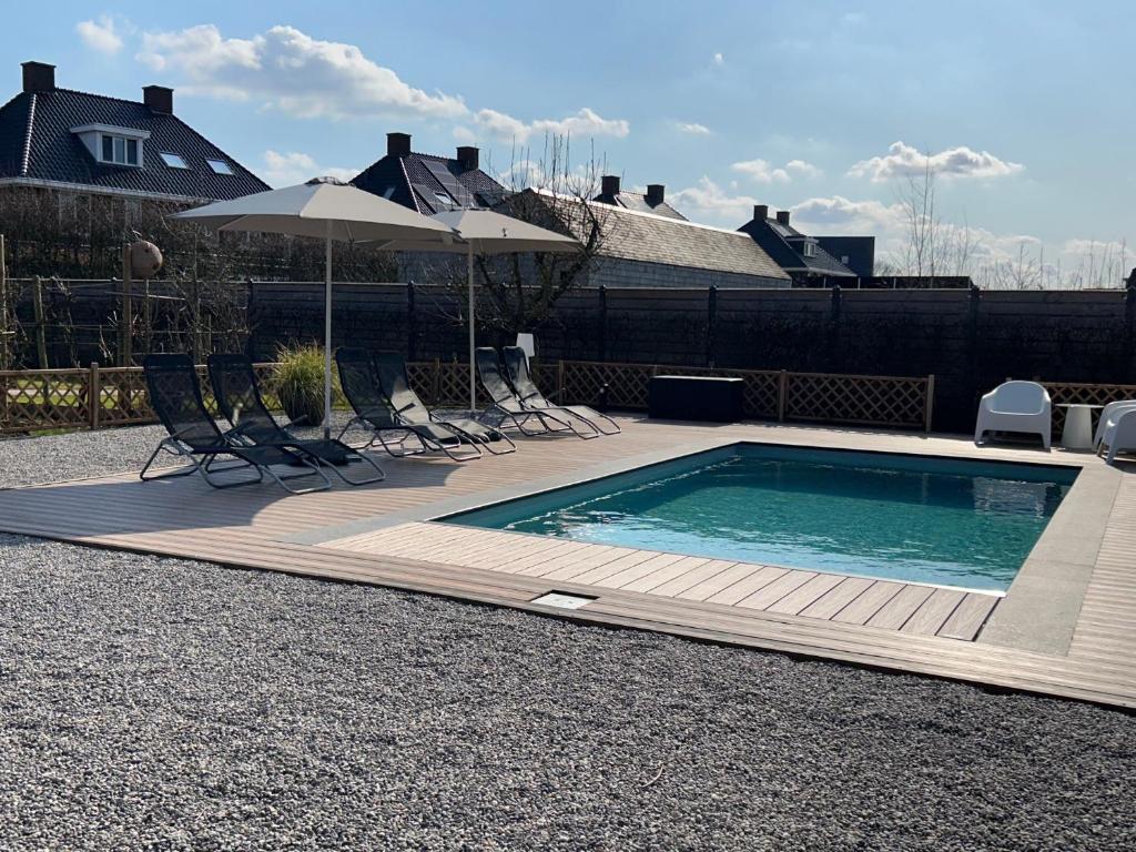 a swimming pool with chairs and an umbrella at Hoeve Altena Barn-House in Woudrichem