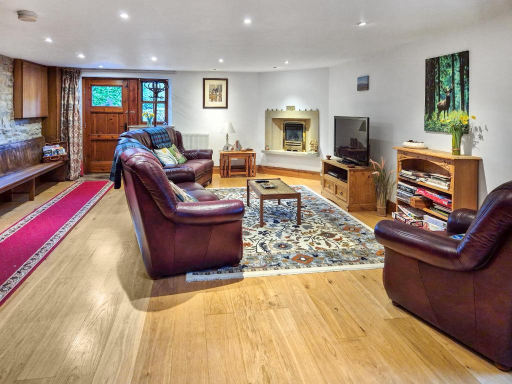 a living room with two leather chairs and a television at Hollin Bank Cottage in Salterforth