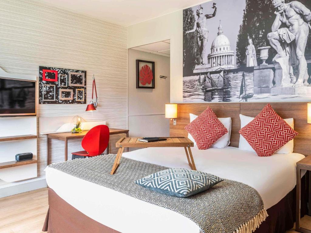 ein Hotelzimmer mit einem Bett und einem roten Stuhl in der Unterkunft Aparthotel Adagio Paris Bercy Village in Paris