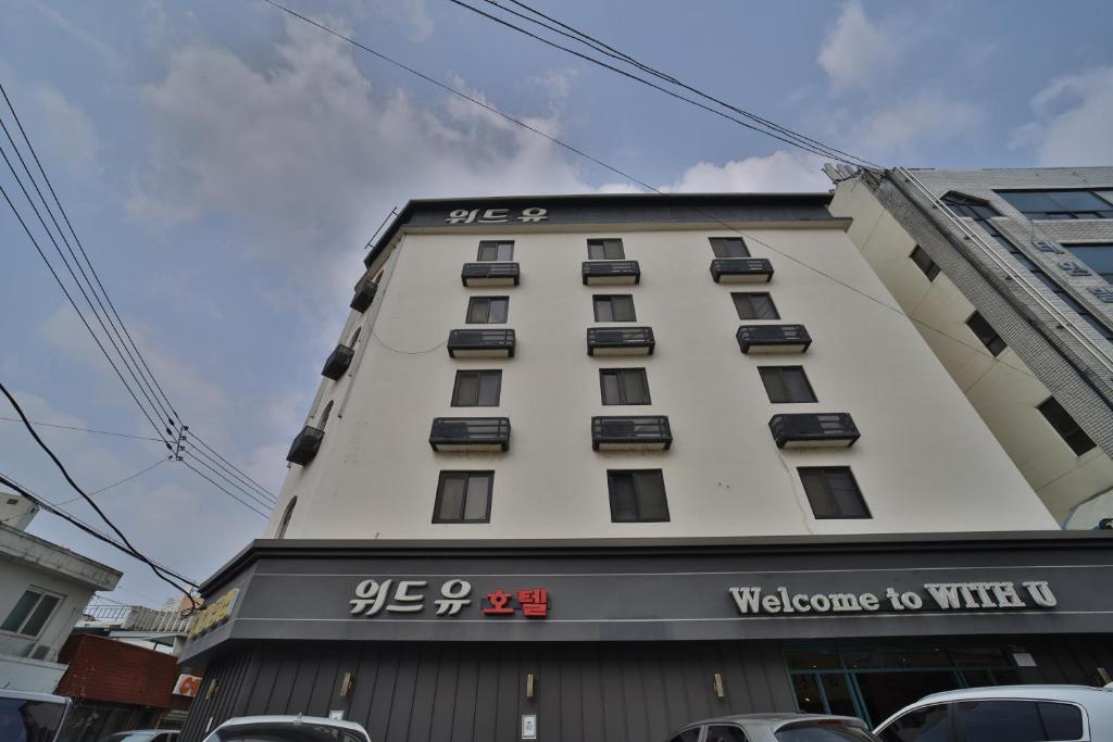 a tall white building with a welcome to mine sign on it at 위드유 호텔 광주역 in Kwangju-yŏk