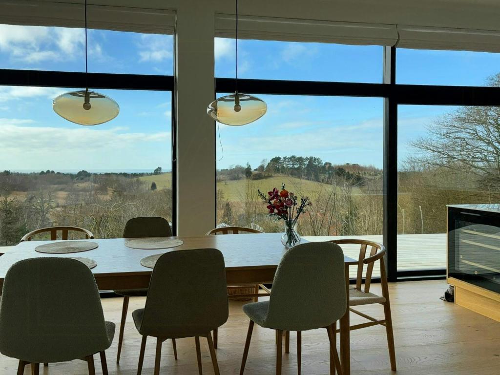 a dining room with a table and chairs and windows at Summer House On Hillside Plot By Sejerø Bay in Fårevejle