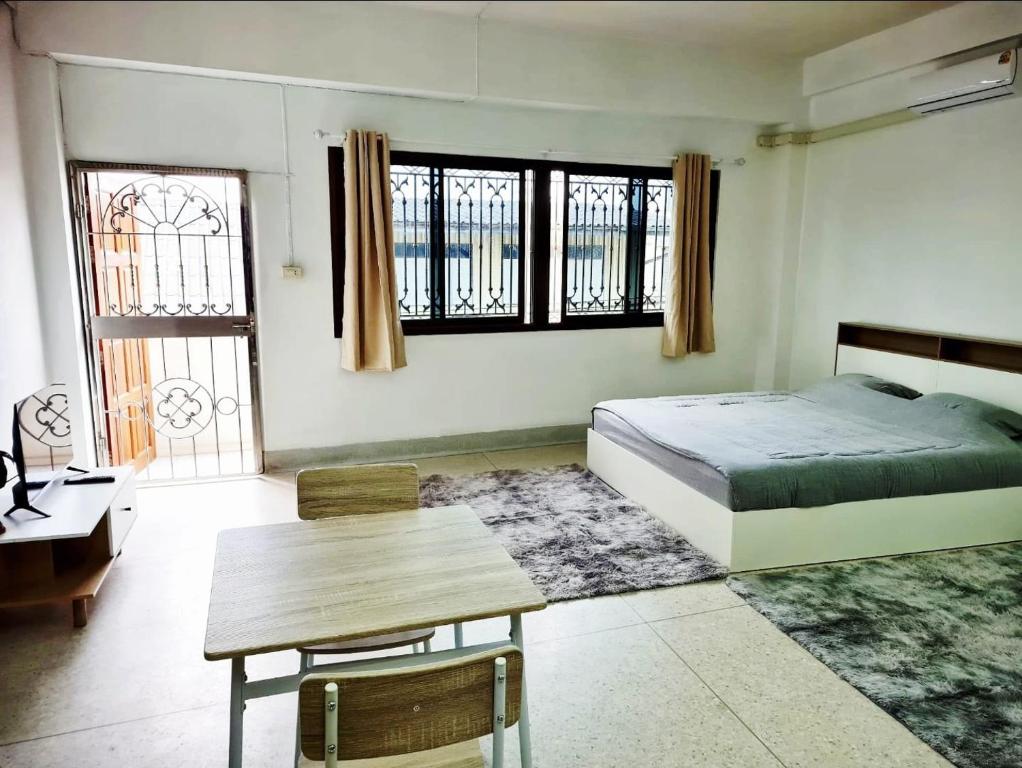 a bedroom with a bed and a table and windows at 57 hua hin in Hua Hin