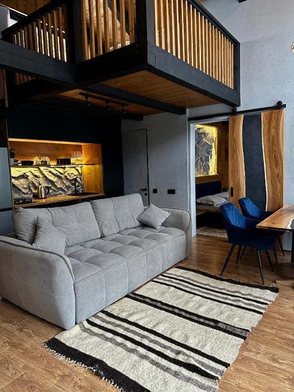 a living room with a gray couch and a rug at Шале Ротило in Krivopolʼye