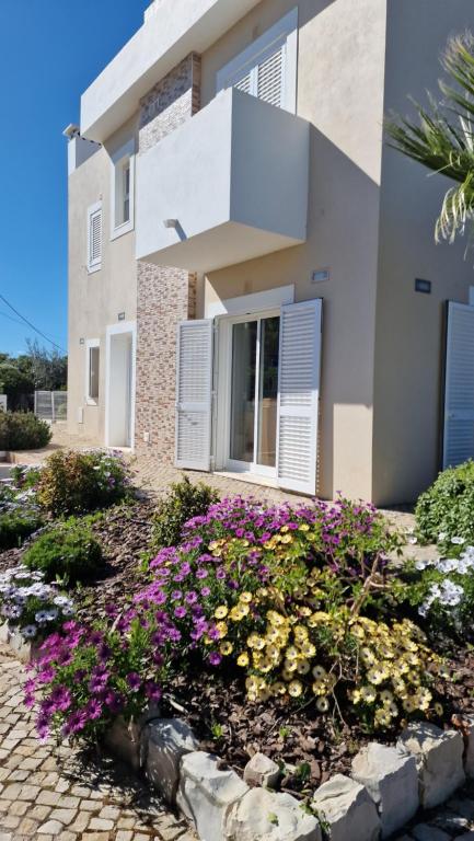 a house with flowers in front of it at Roots Villa - Casa das Árvores in Cabanas de Tavira