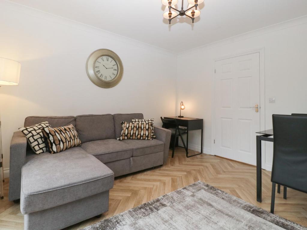 a living room with a couch and a clock on the wall at 42 Ynys Y Nos in Neath