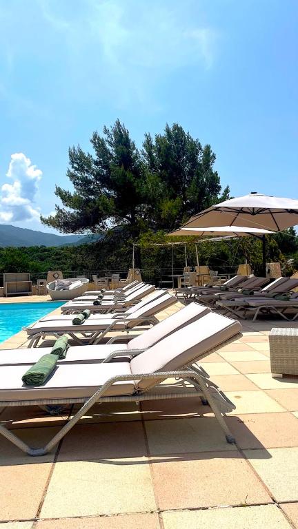 a row of lounge chairs and an umbrella next to a pool at Hotel & Appartements Acqua Dolce in Porticcio