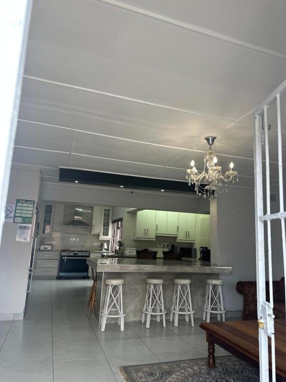 a large kitchen with a counter and stools in it at Abebe Guest House in George