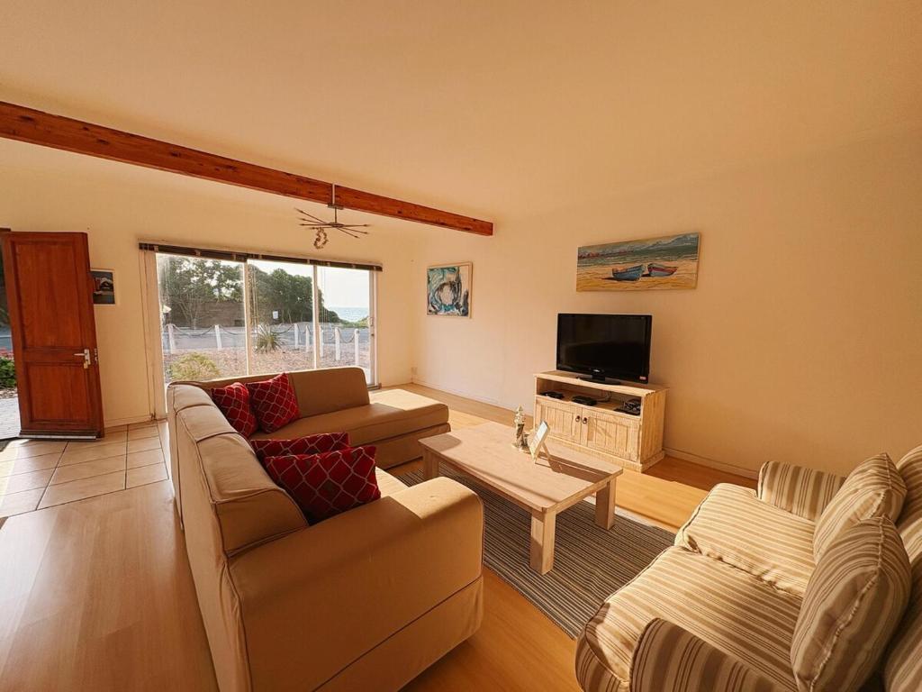 a living room with two couches and a tv at Linga Longa in Britannia Bay