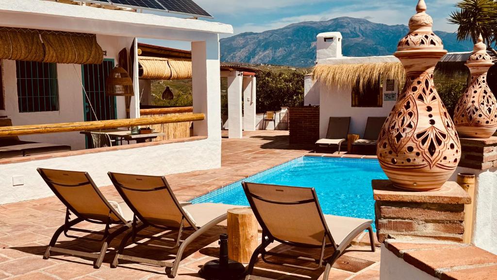a pool with chairs and a large vase next to a house at Casa Bambú Boutique Studios Andalusië with pool and Mountain Views in Vélez-Málaga