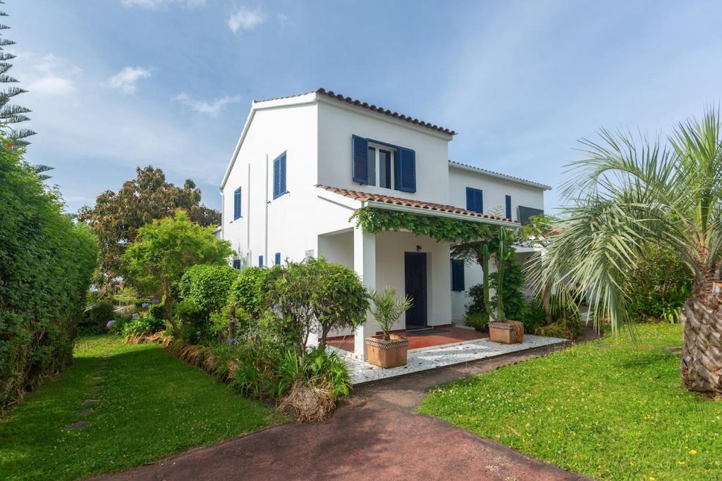 a white house with blue windows and a yard at Casa Silke in Vila Franca do Campo