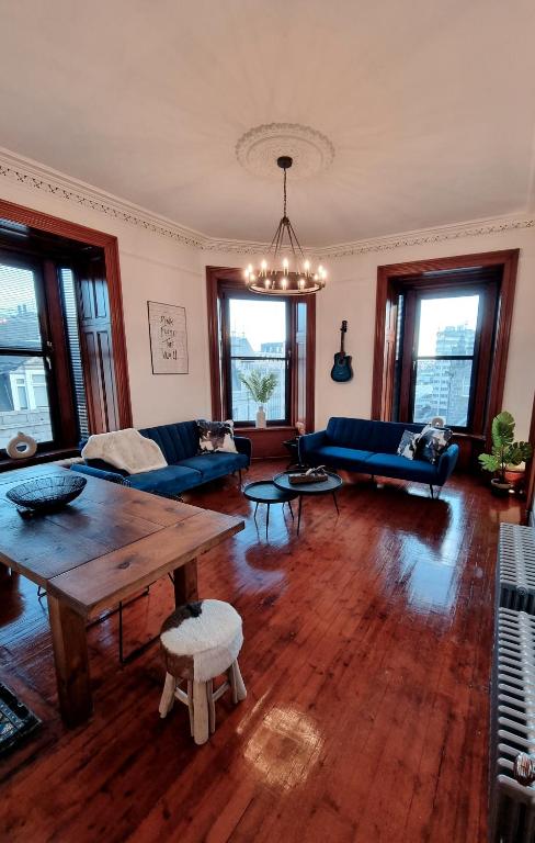 a living room with a wooden table and blue couches at Luxury 2 bedroom city centre apartment with panoramic views and high ceilings in Aberdeen