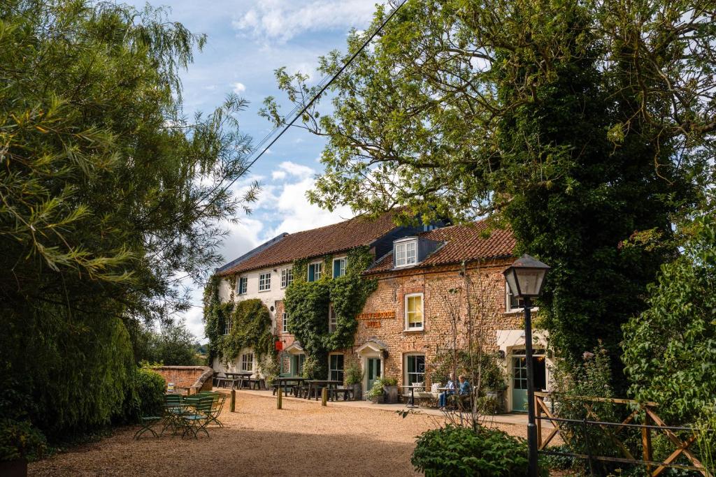 a large stone building with trees in front of it at Sculthorpe Mill in Fakenham