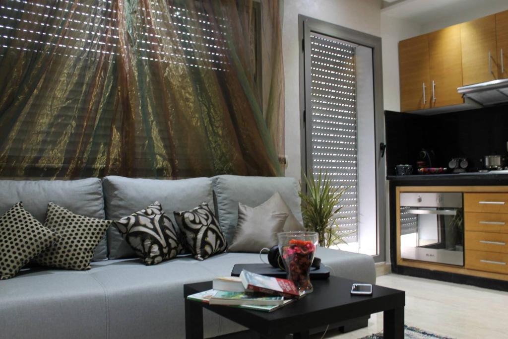 uma sala de estar com um sofá com almofadas e uma mesa em Appartement Mogador em Casablanca