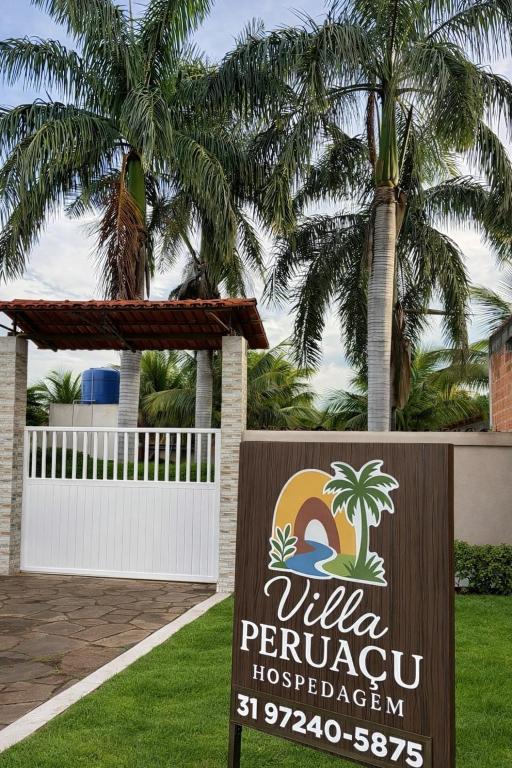 a sign for a hotel with palm trees in the background at Pousada Villa Peruaçu - Na entrada do Parque Nacional Cavernas Peruaçu in Januária